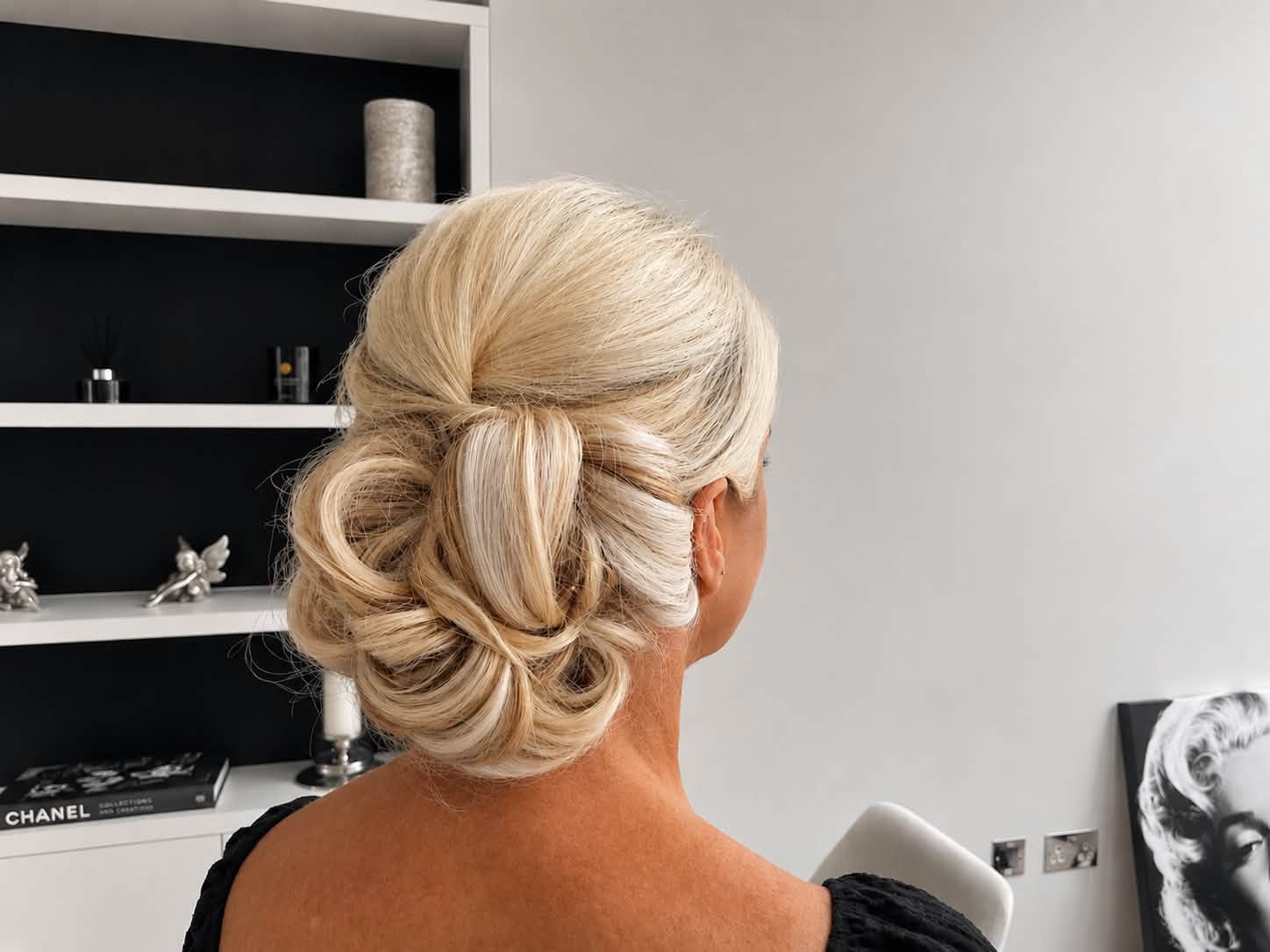 Blonde hair swept into an intricate low updo, rear view