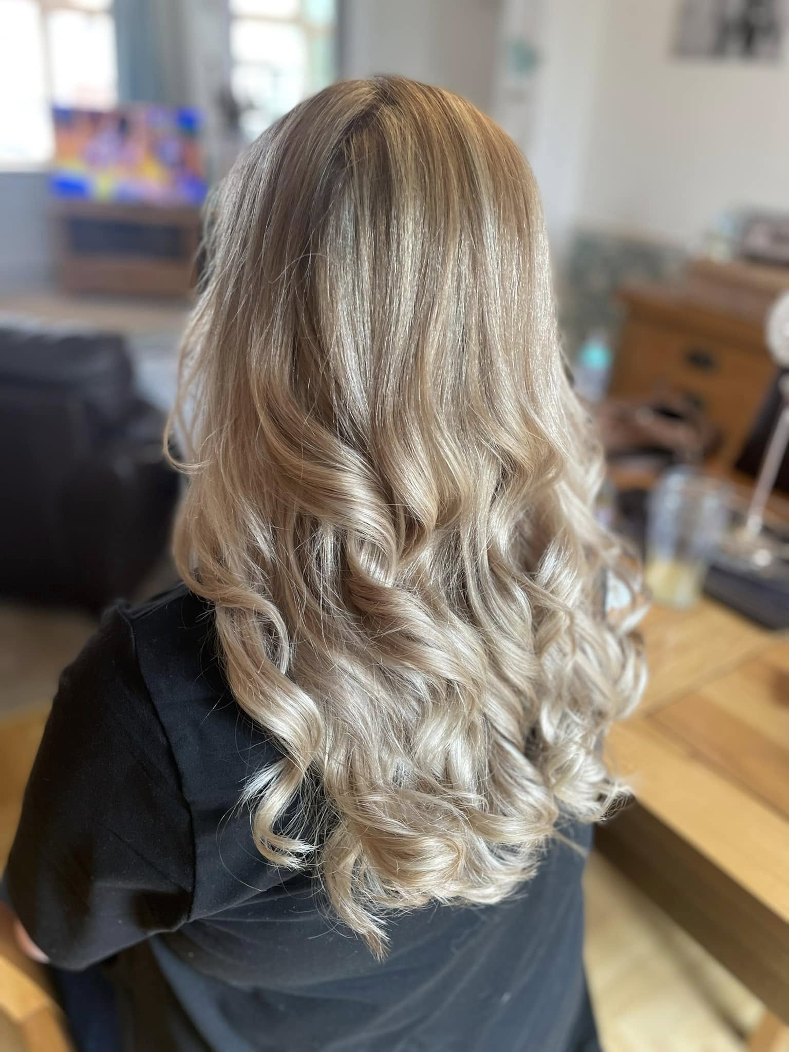 Long blonde hair styled into soft, glossy curls
